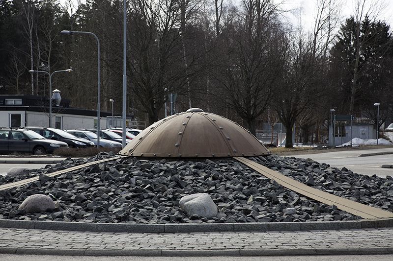 En rund form liknande en hjälm som ligger ovanpå stenar.