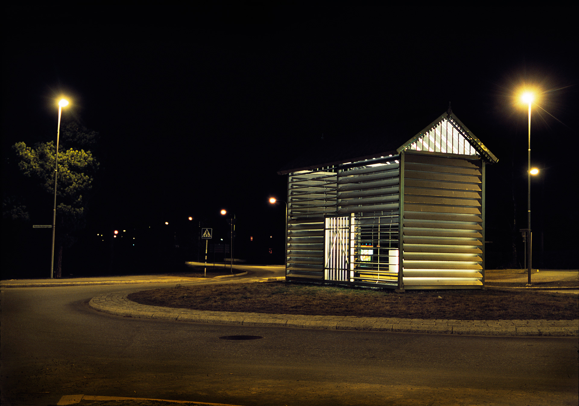 Ett hus som lyser i mörkret. Står i en rondell.