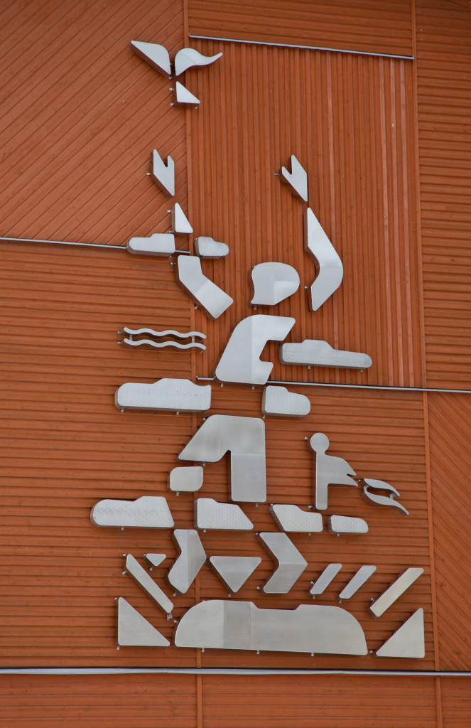 Plåtbitar formade till en människa på en röd vägg.