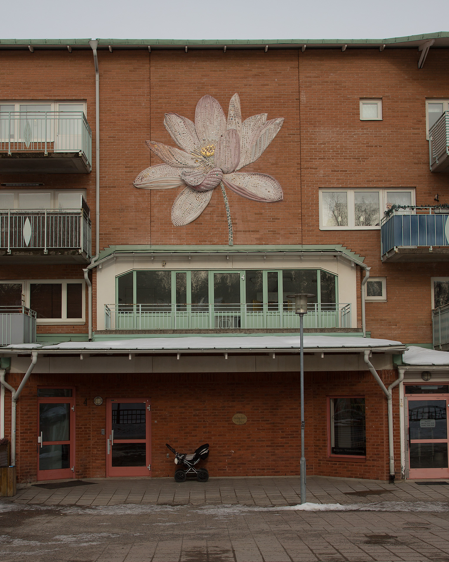 En stor rosa blomma på en röd tegelfasad.
