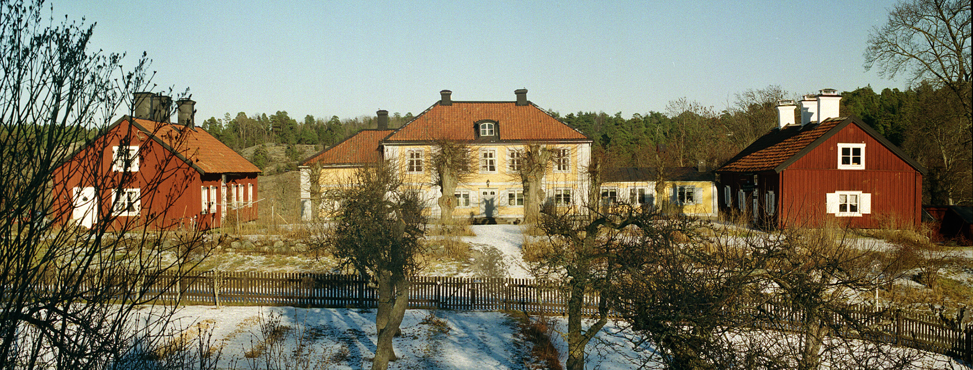 Tre hus som står på rad innanför ett staket.