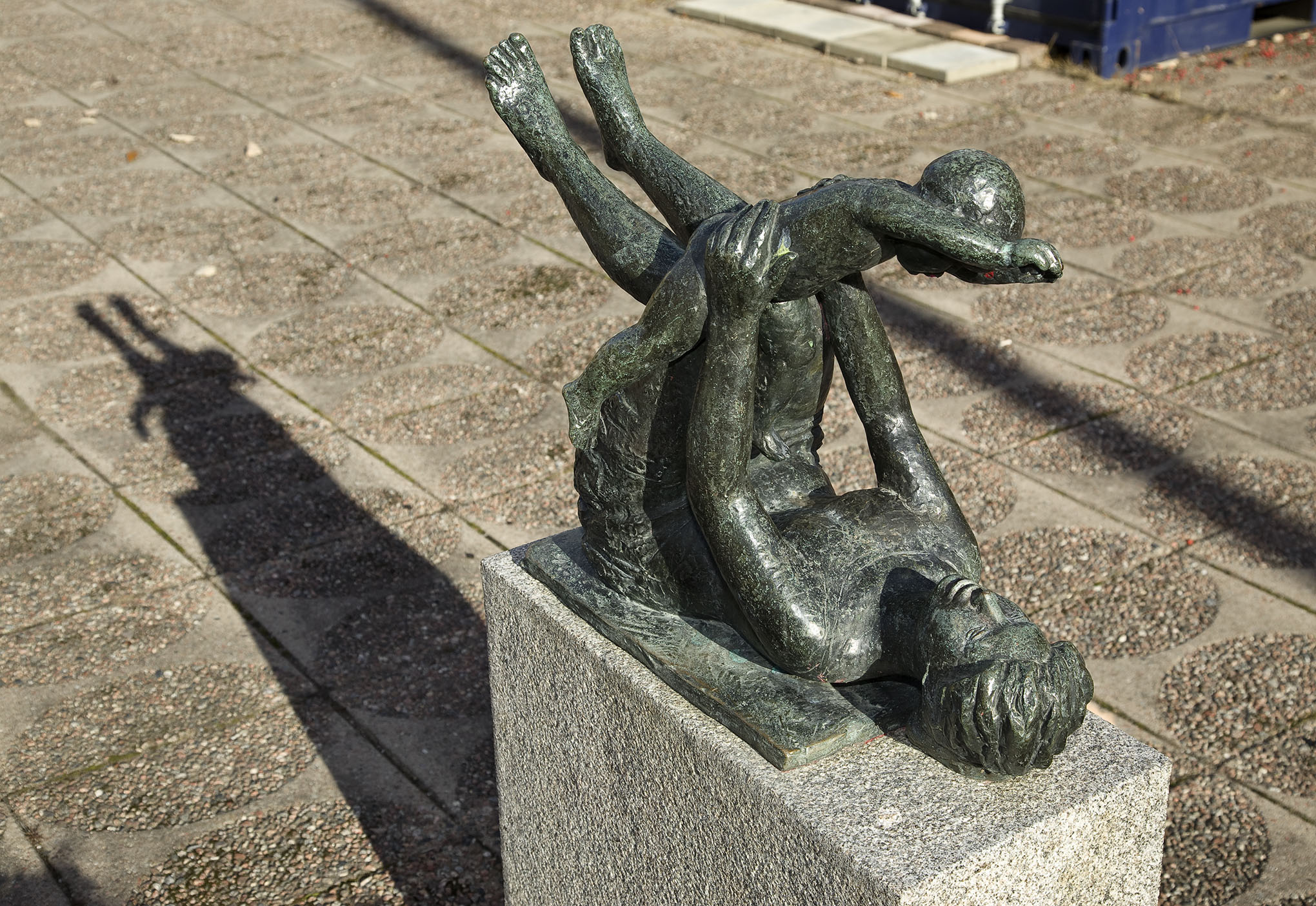 En Skulptur av en kvinna som ligger på rygg och håller ett barn i händerna.