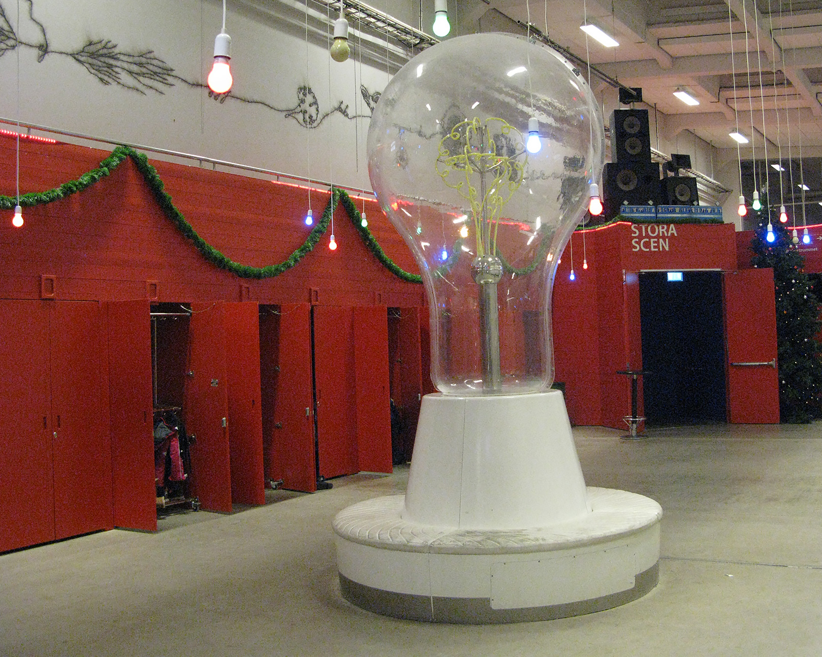 En stor glödlampa inomhus med en vit sittbänk runtom.