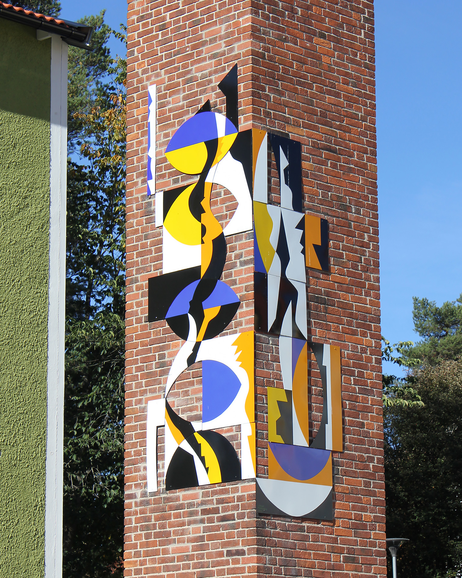 Plattor i olika former och färger som blått, gut och vitt på en hög pelare gjord av tegel.