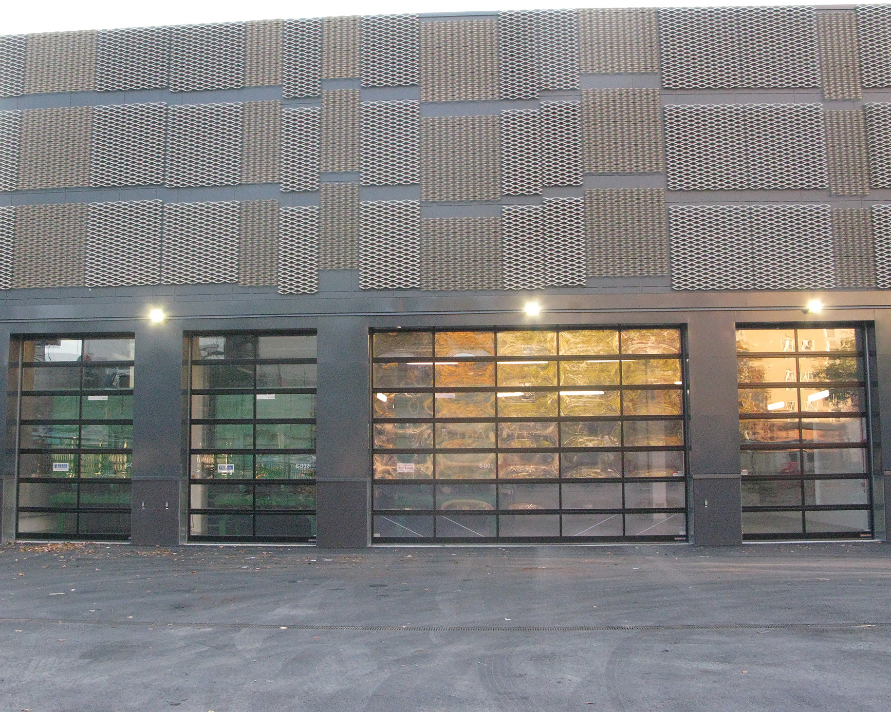 En husvägg med brun metall på fasaden och stora fönster längst ner mot marken.