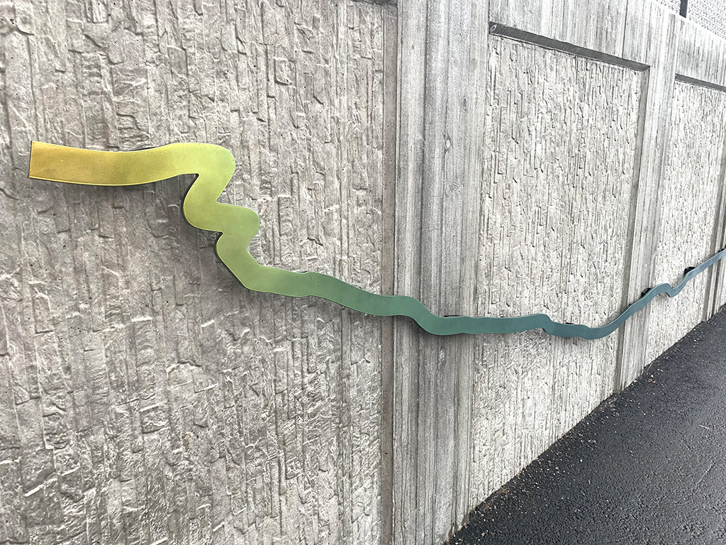 En linje i gult och grönt på en grå vägg.