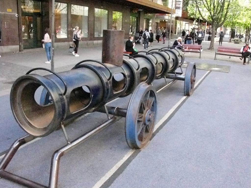 Ett tåg i miniformat i stadsmiljö som står på räls.