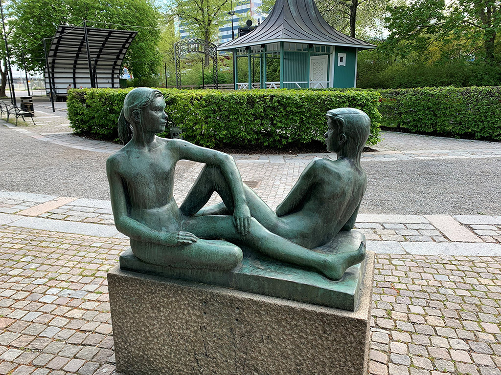 En flicka och en pojke sitter mitt emot varandra. Båda är nakna, deras kroppar är smärta och vältränade.