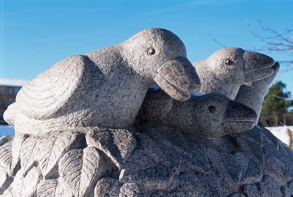 Fåglar av sten som sitter på stiliserades blad.