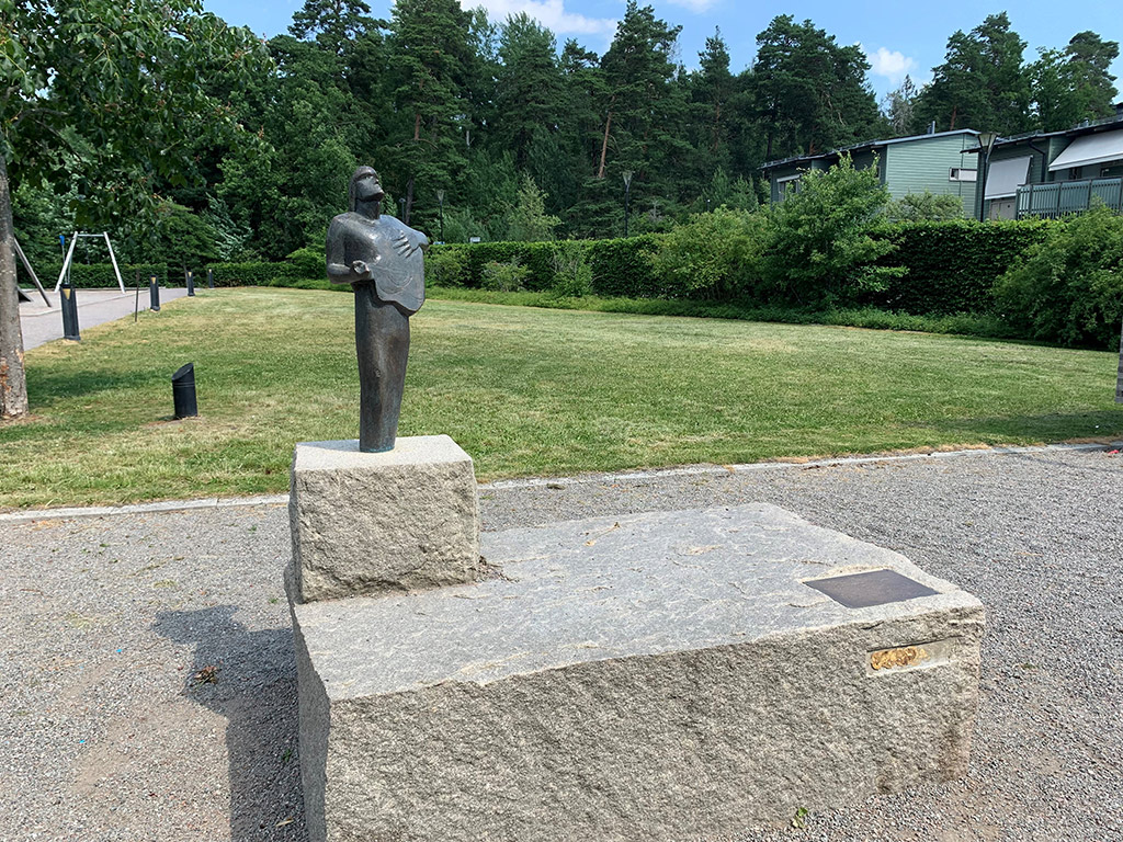 Bronsskulptur med gestalt som spelar gitarr.