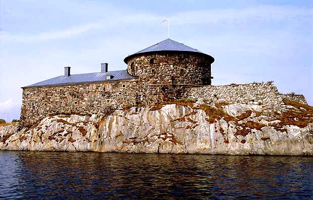 Ett hus byggt av stenar. Det är byggt på klipporna vid havet.