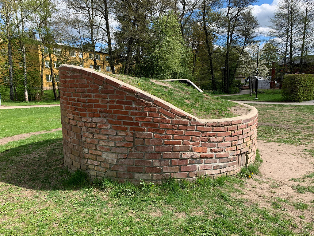 En rund byggnad av tegel med gräs ovanpå.