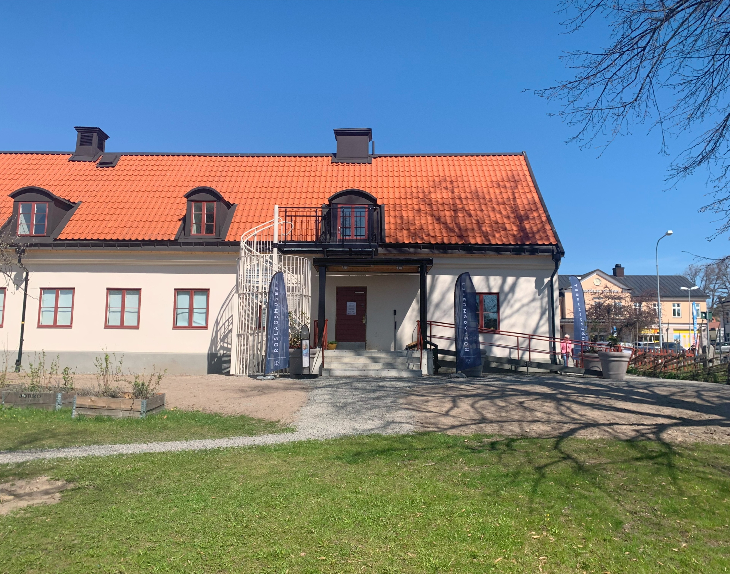 Ett avlångt envåningshus med rund brandtrappa till en av vindsvåningens takkupor. En rullstolsramp leder upp till entrén.
