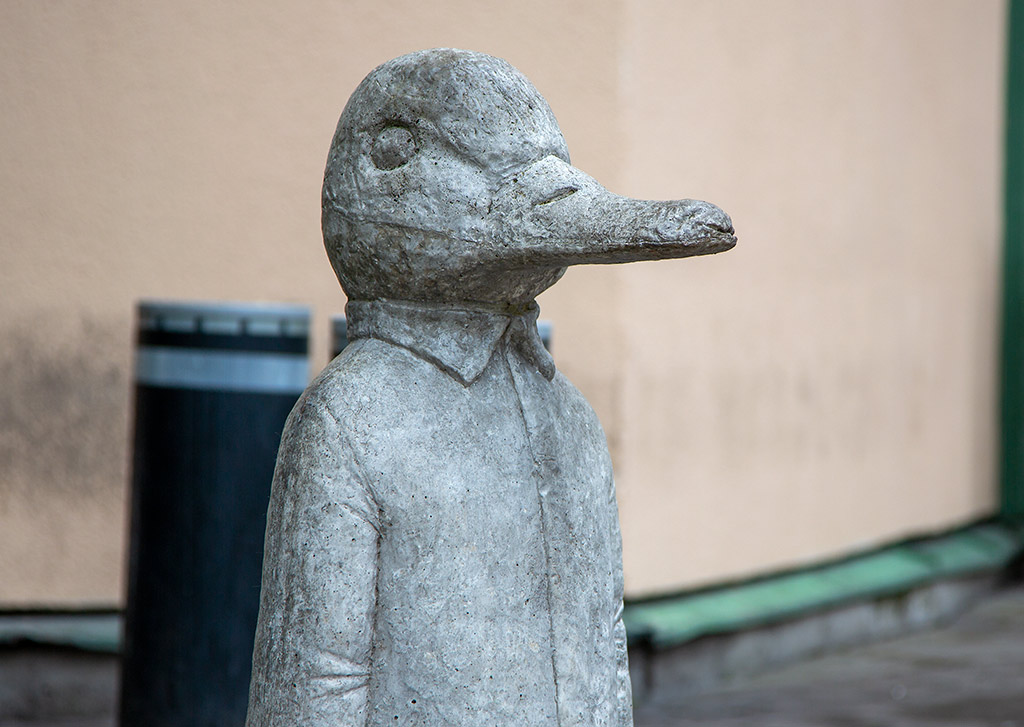 Skulptur av en and i grå betong.