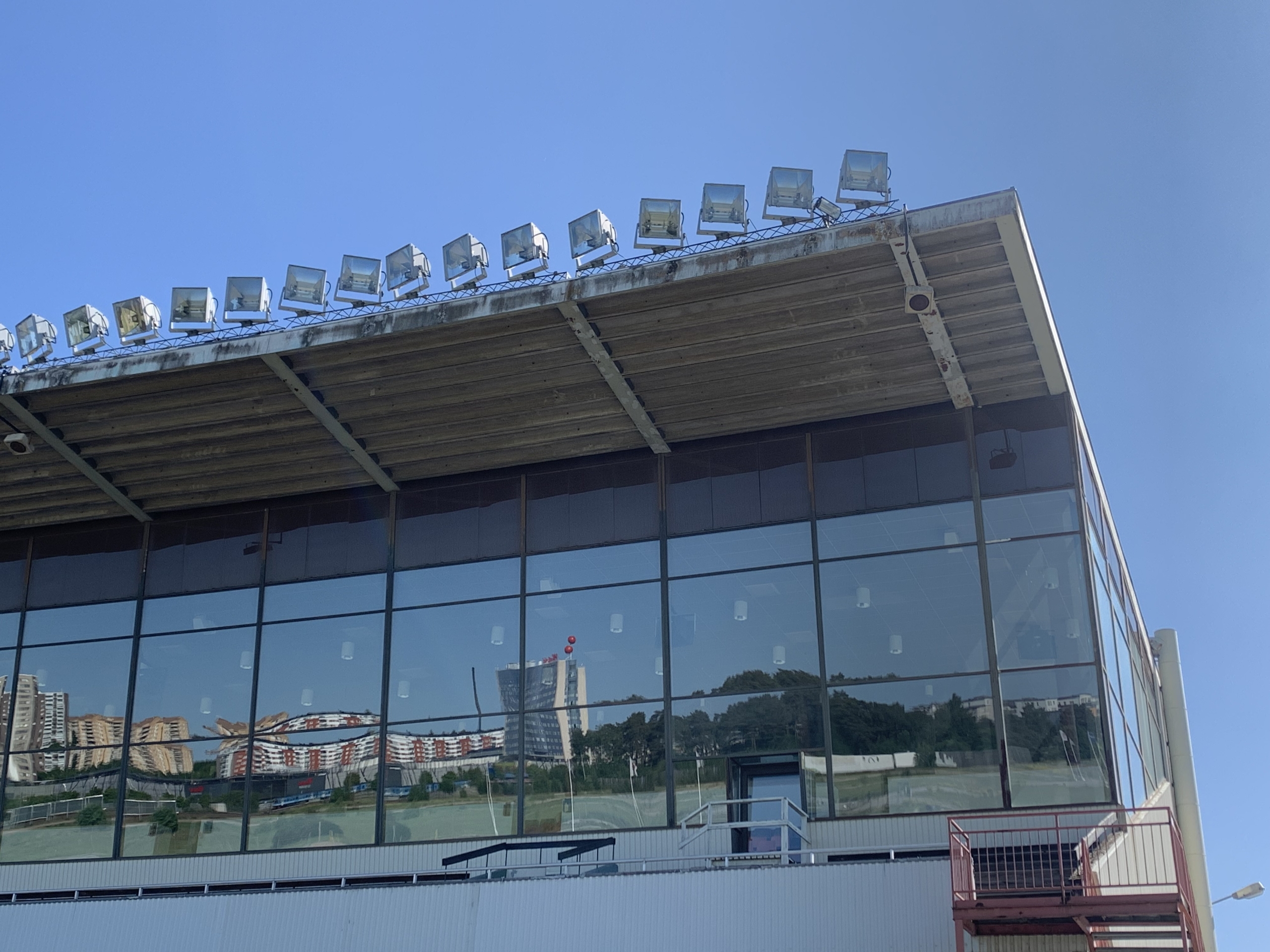 Gaveln på läktaren på Täby galopp. Stora fönster reflekterar en bild av Täby centrum. Längs med taket syns strålkastare.