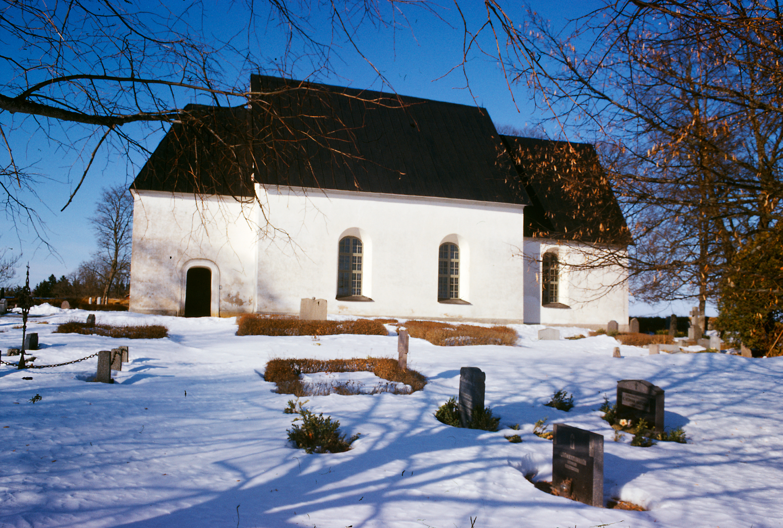 Exteriör av putsad, vit kyrka.
