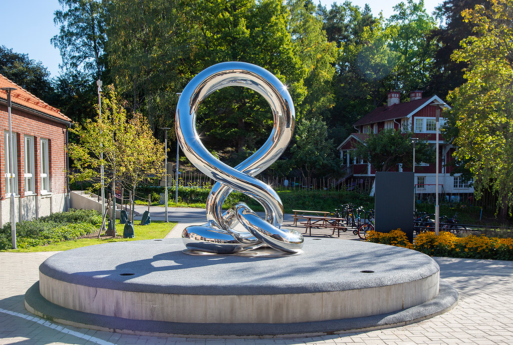 En silverglänsande skulptur som liknar en snirklig åtta står på en rund plattform.