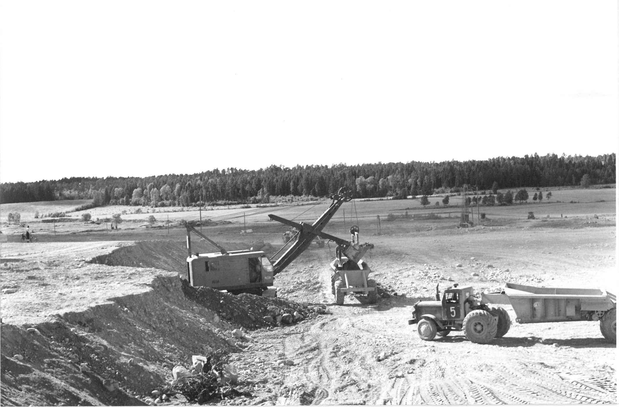 En gammaldags grävmaskin skopar upp schaktmassor på en trailer.