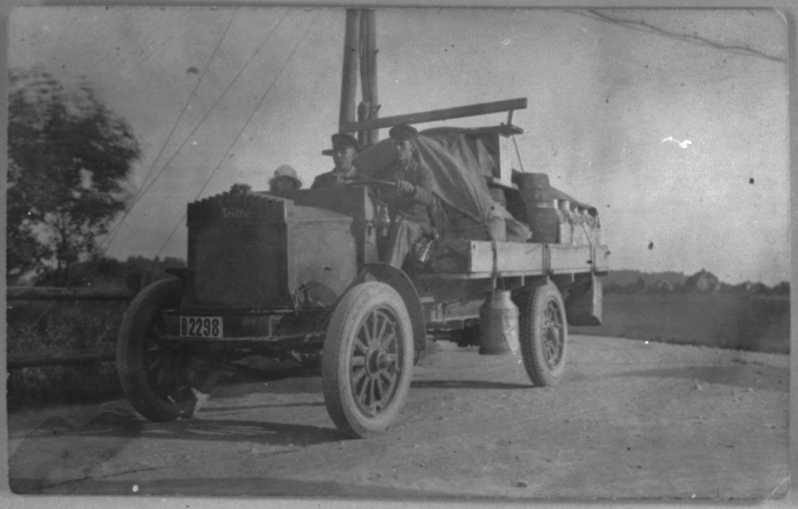 En gammal lastbil med stora mjölkkannor i metall. Några hänger från bilen.