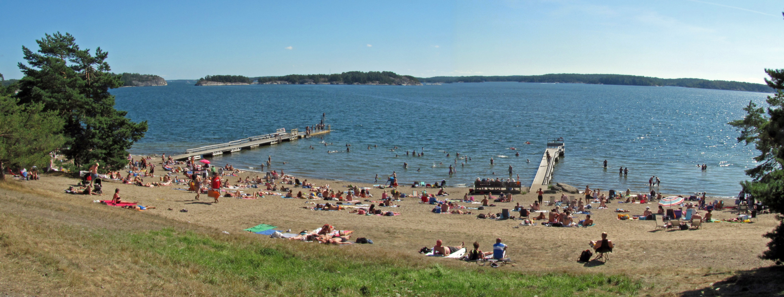 Utsikt över strand och hav med människor som solar.
