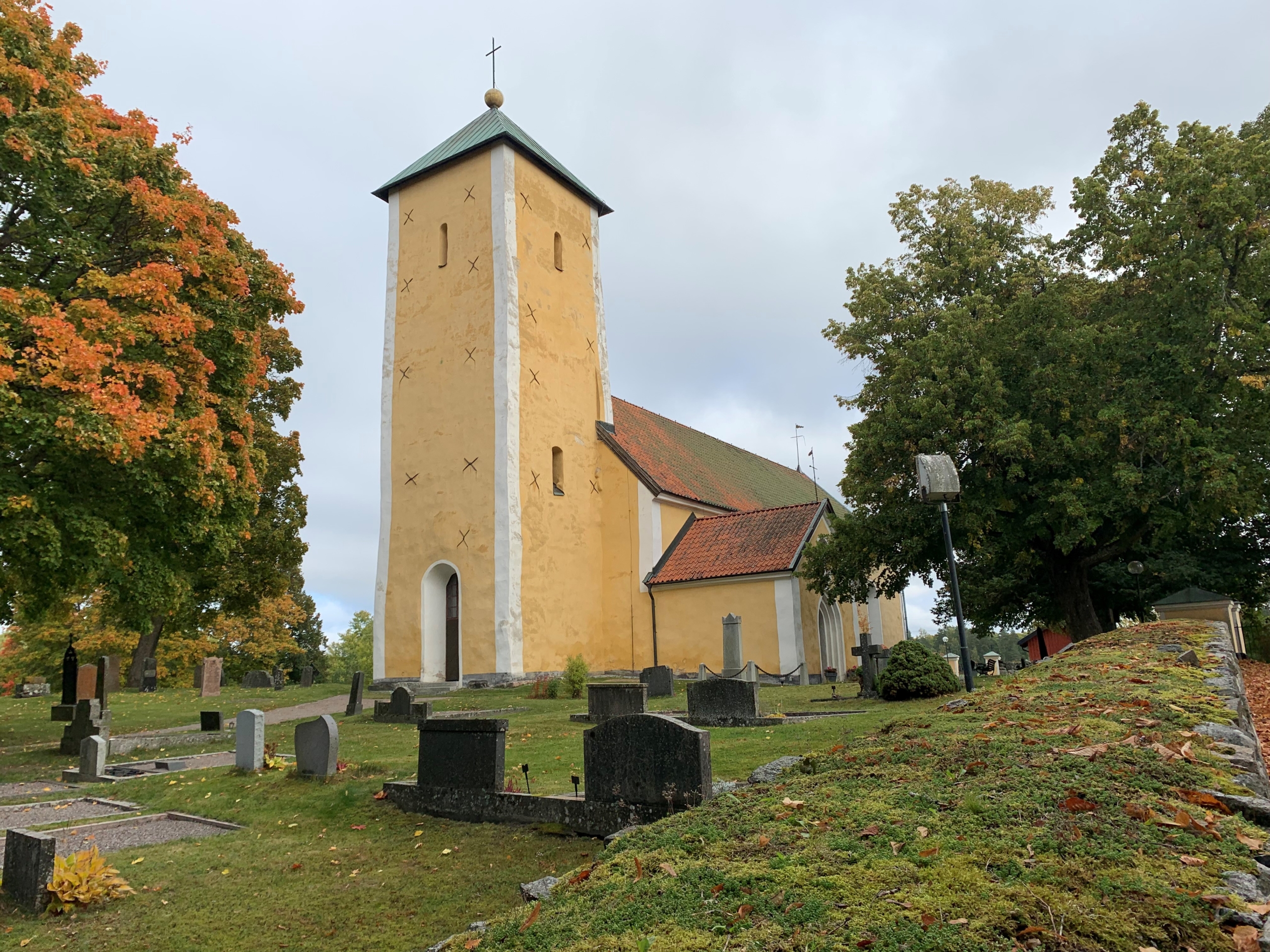 En medeltida kyrka på en höjd, fasaden är solgul i färgen.
