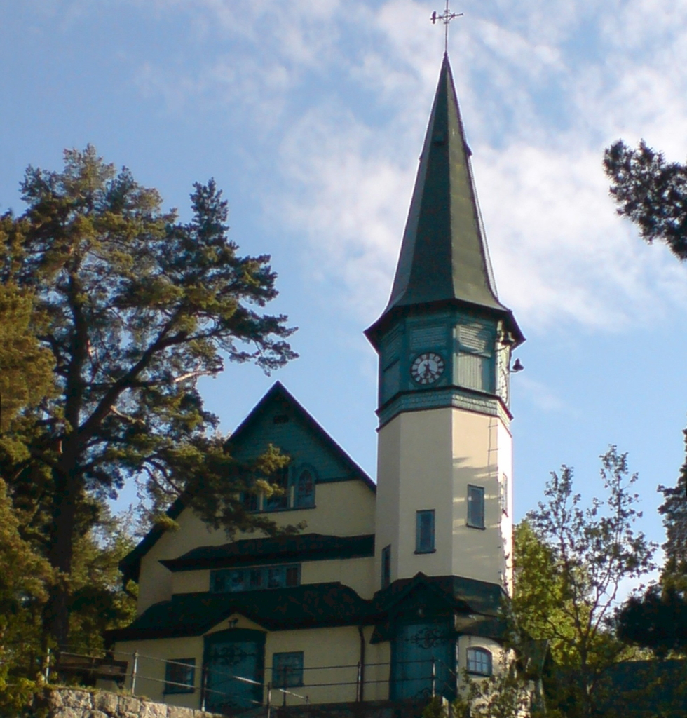 Färgfoto av kapell i beige puts och koppar detaljer med ett torn.