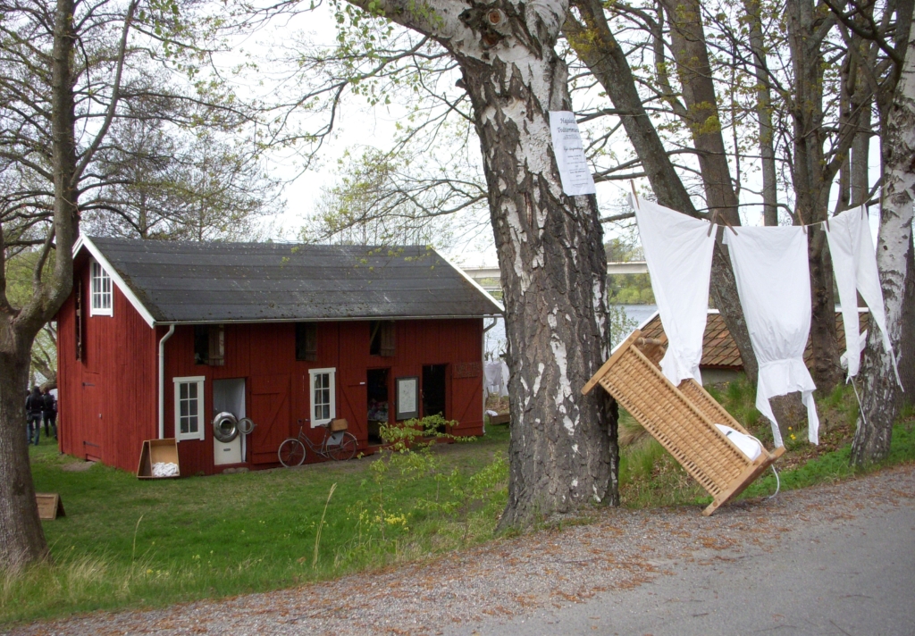 Röd träbyggnad med ett tvättsträck uppsatt mellan två träd.