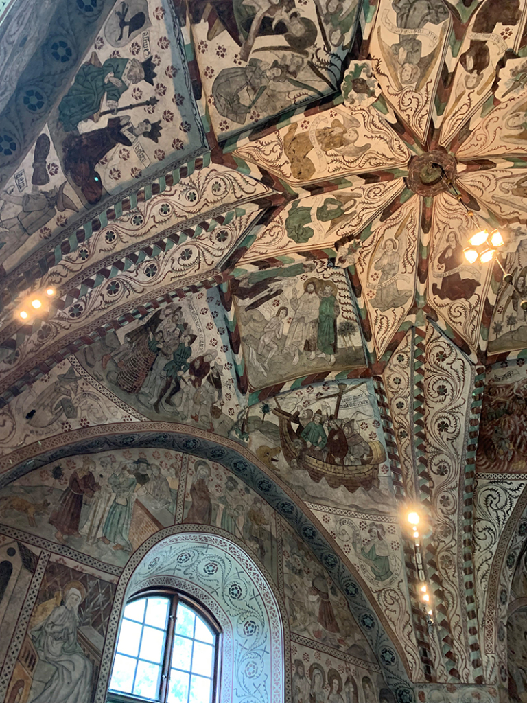 Detaljbild från kalkmålningar i taket i Odensala kyrka med fönster längst ner till vänster.