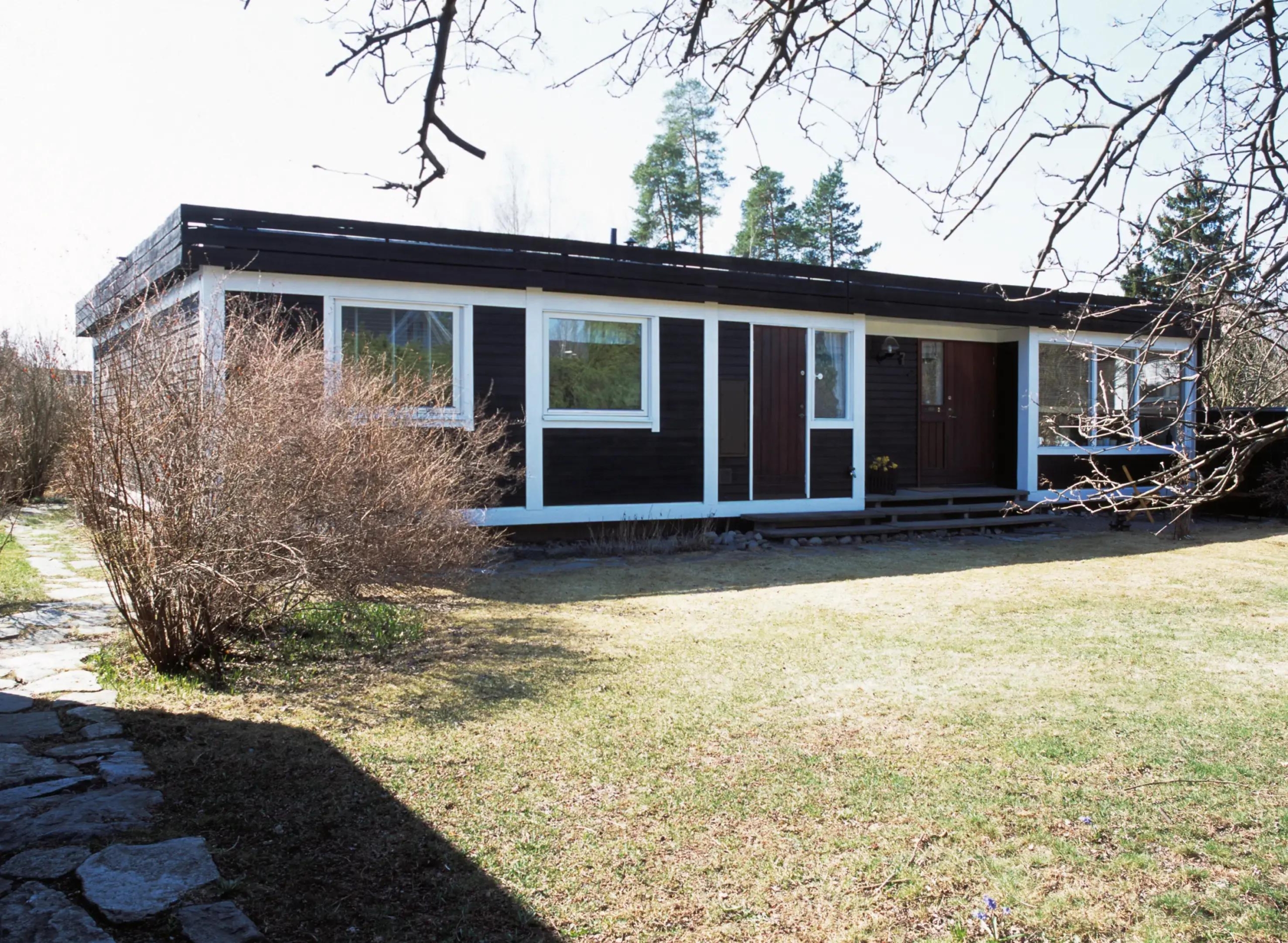 Enplansvilla i mörkt trä med vitaknutar.