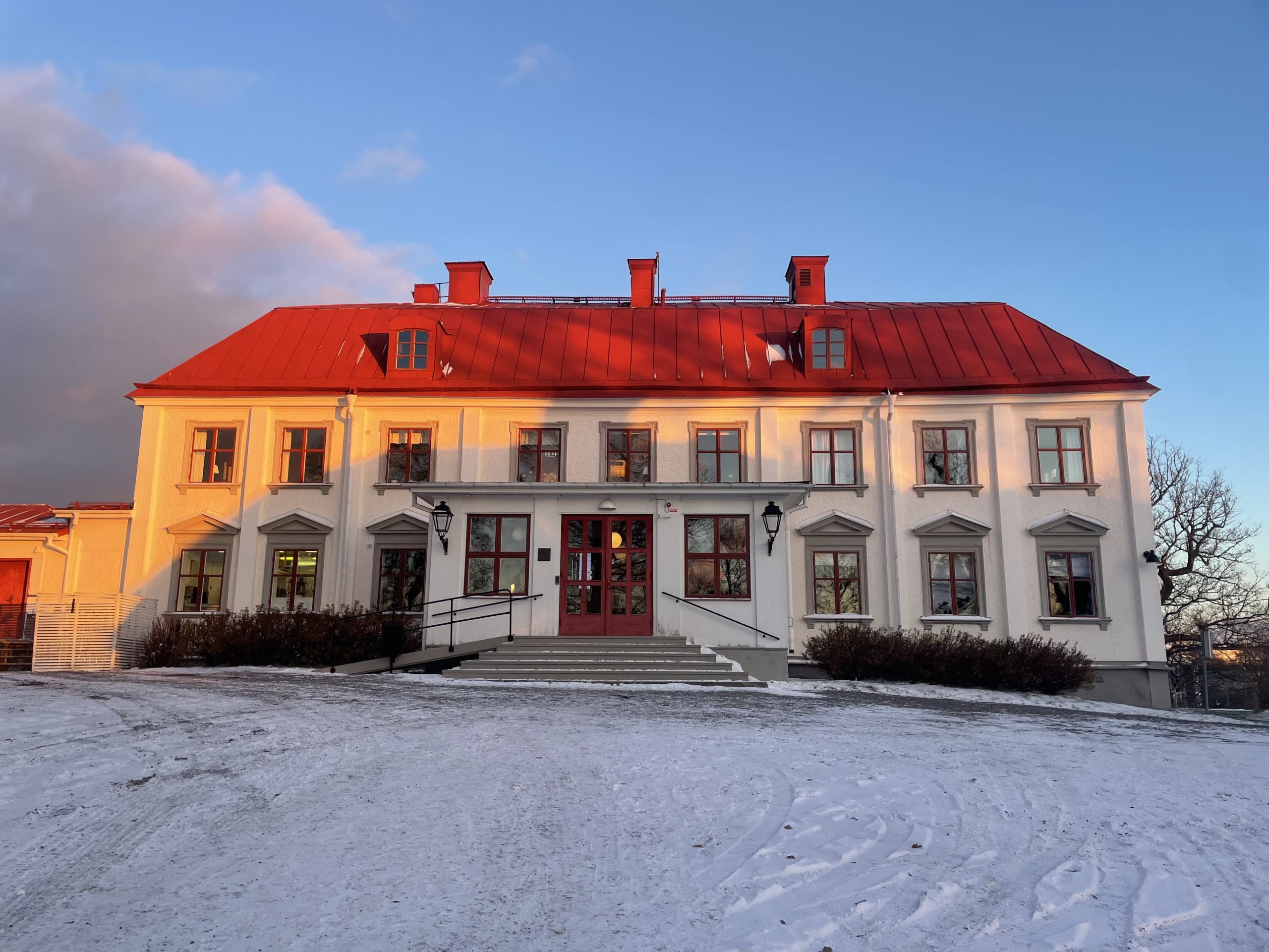 Herrgårdsbyggnad i vit puts med rött plåttak.