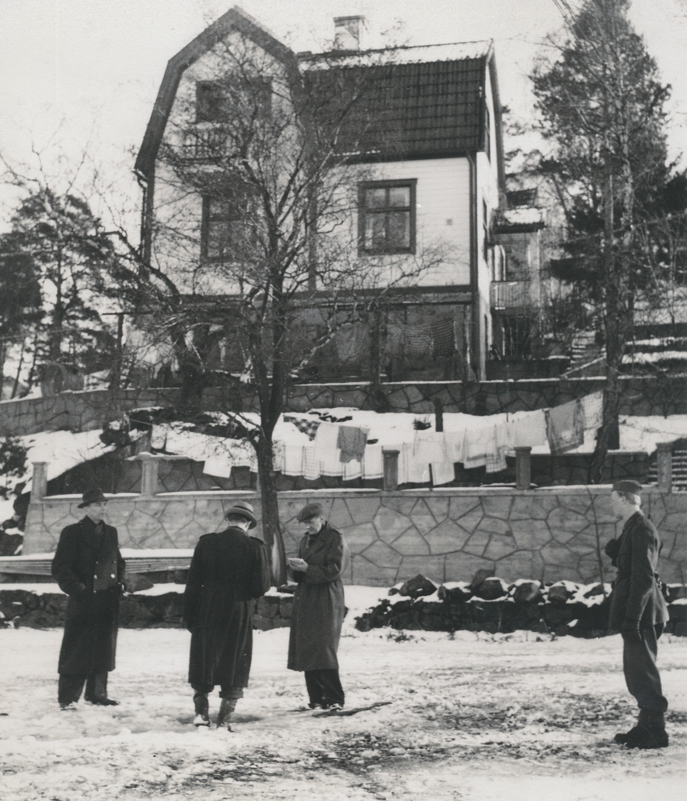 Fyra män står framför en högt belägen villa.