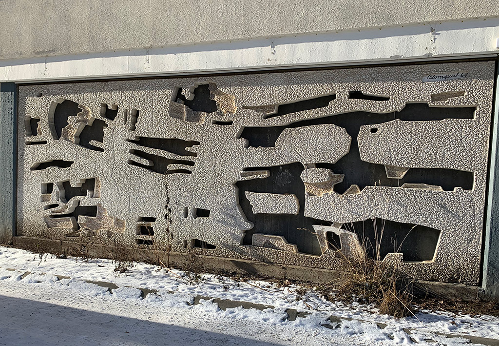 Väggkonst av ljus sjösten med utskurna mörka hål i oregelbundna former.