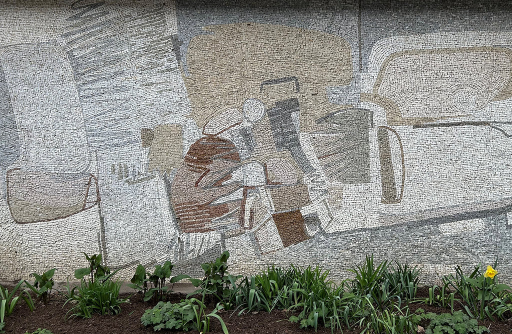 Abstrakt konst av mosaik på vägg. Bruna och beiga färger.