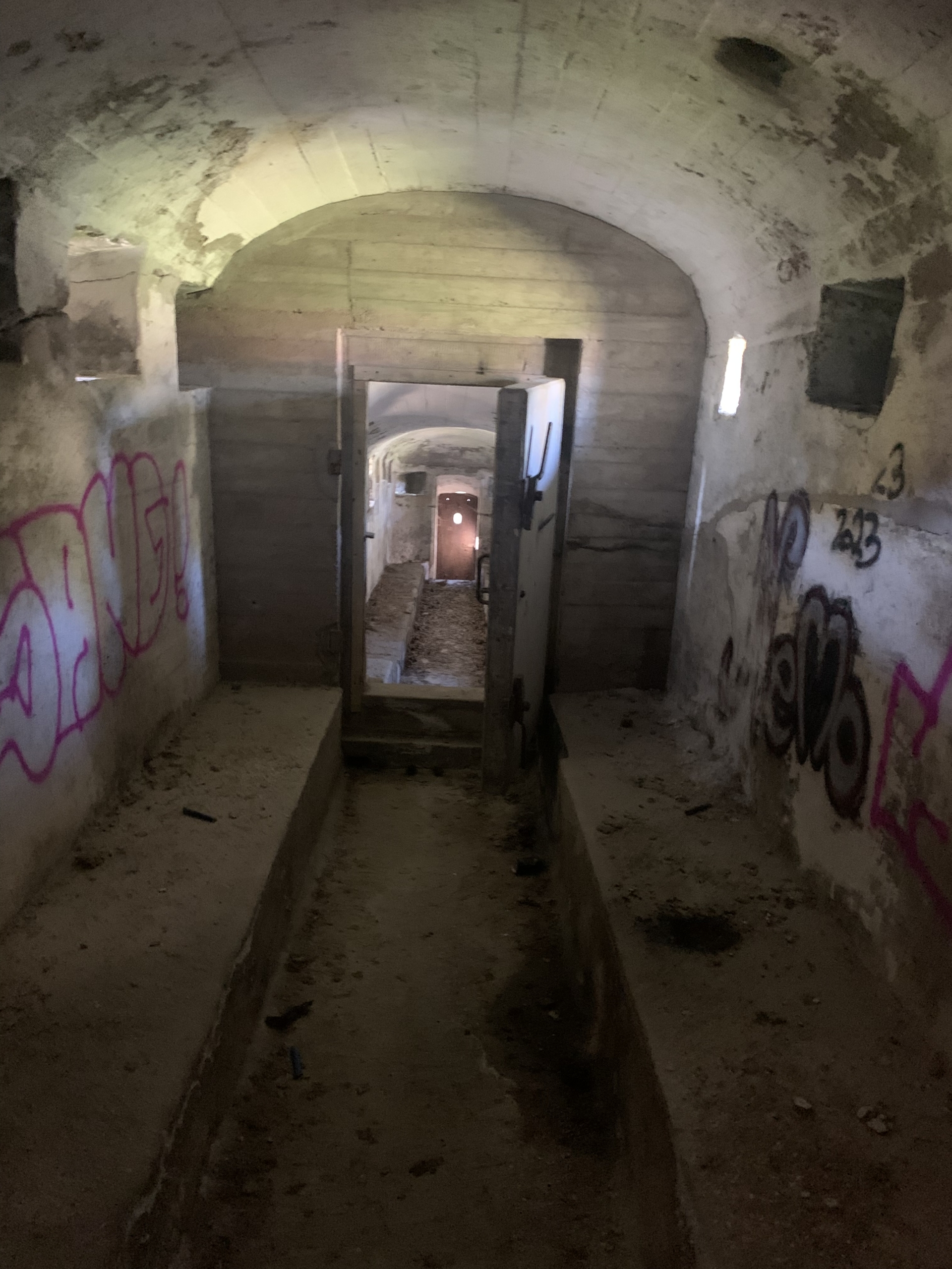 Ett långt rum med bänkar längs väggarna och stenväggar.