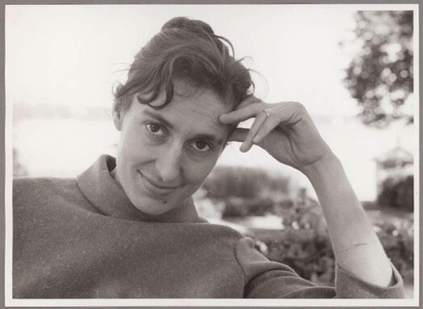 En ung kvinna i polotröja ler mot kameran. I bakgrunden syns havet.