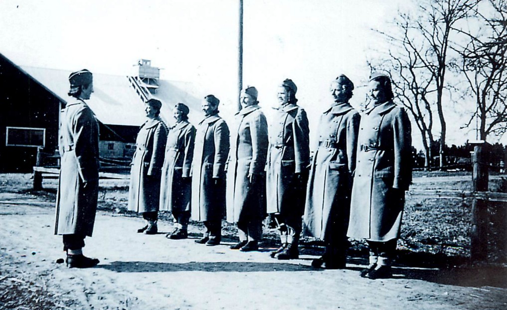 Sju kvinnor i rockar står i givakt framför sitt kvinnliga befäl.