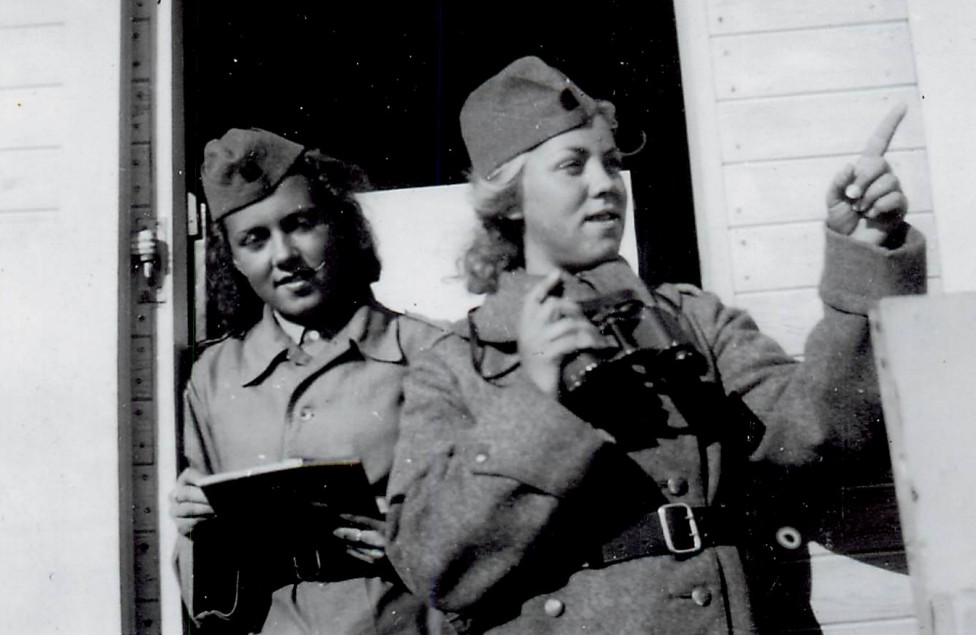 Två kvinnor i uniform, en med kikare.