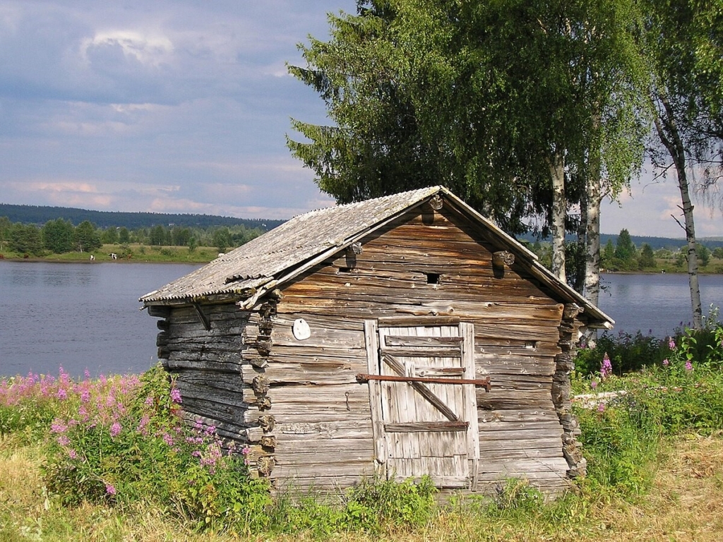 Ett timrat hus framför Torneälv.