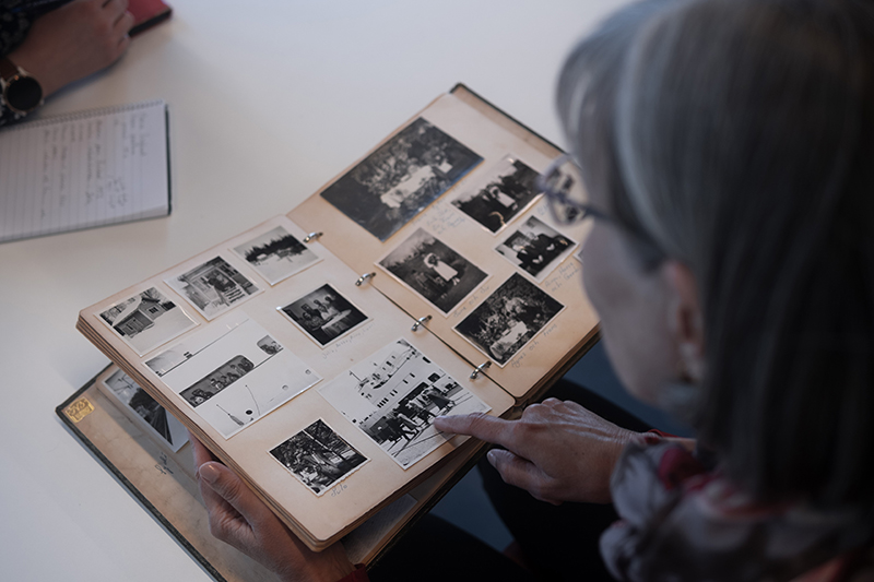 En kvinna tittar på svartvita fotografier i ett fotoalbum.