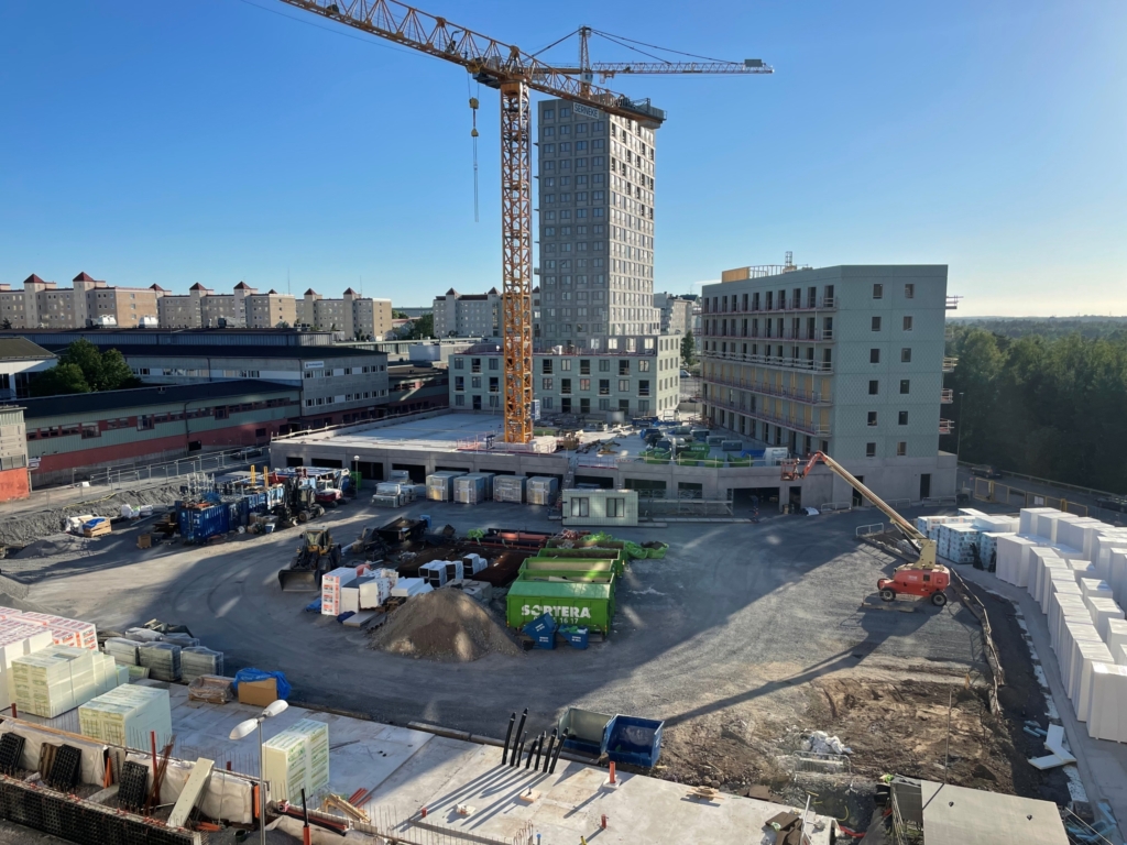 Byggarbetsplats med lyftkran framför ett höghus.