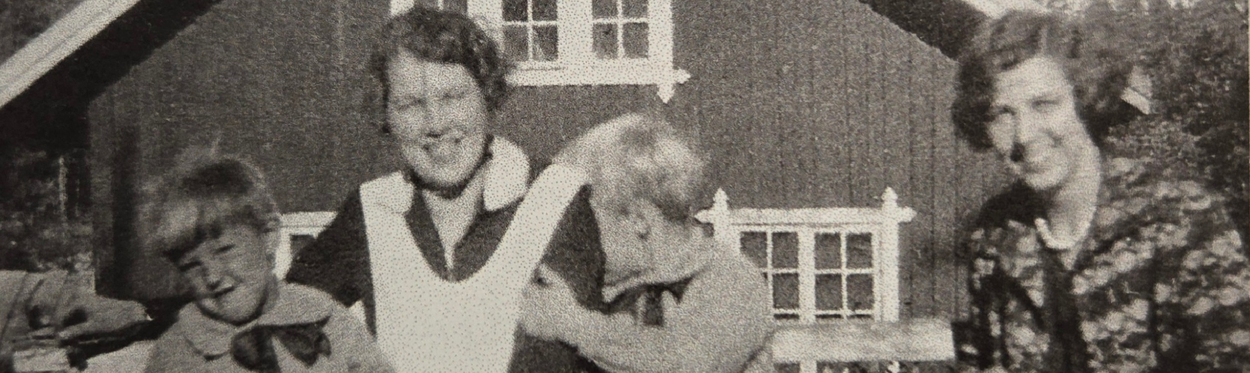 Foto som visar två kvinnor och två barn som sitter på en bänk framför kvarnbyggnaden.