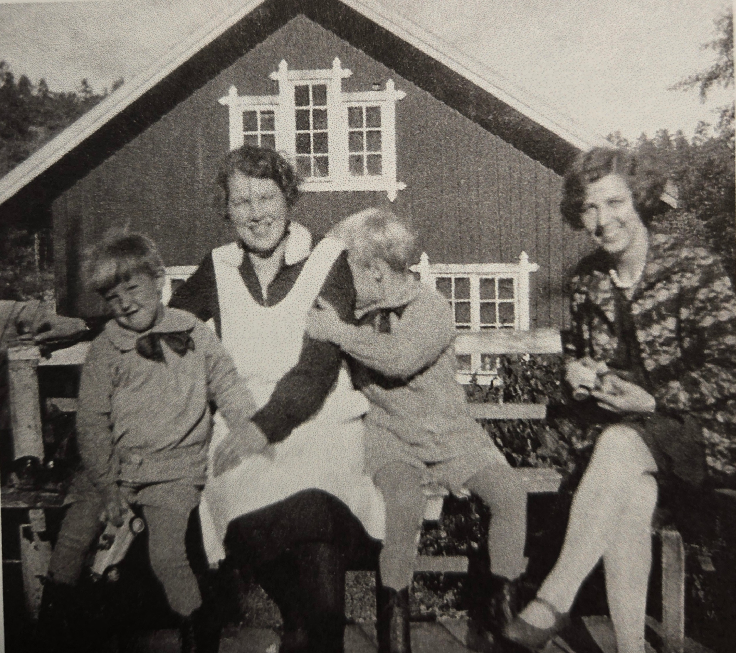 Foto som visar två kvinnor och två barn som sitter på en bänk framför kvarnbyggnaden.
