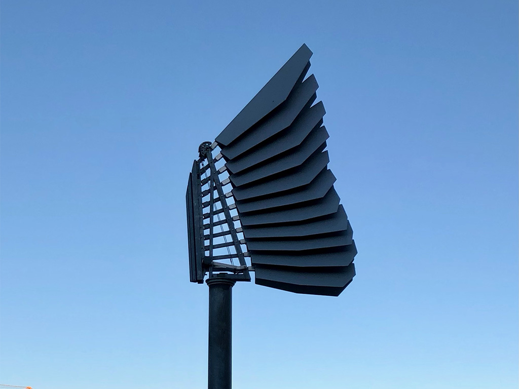 Skulptur i grått veckad stål mot en blå himmel.